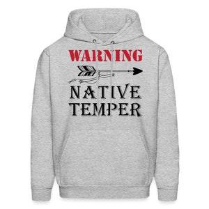 Puede incluir: Una sudadera con capucha gris con el texto "WARNING NATIVE TEMPER" en letras negras. Una flecha con un dise&ntilde;o de pluma apunta hacia la derecha.