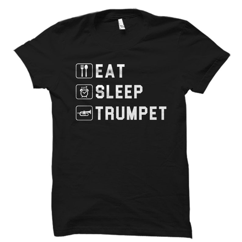 Pode incluir: Camiseta preta com texto branco que diz "Eat Sleep Trumpet" com um garfo e faca, um rosto dormindo e um &iacute;cone de trompete.
