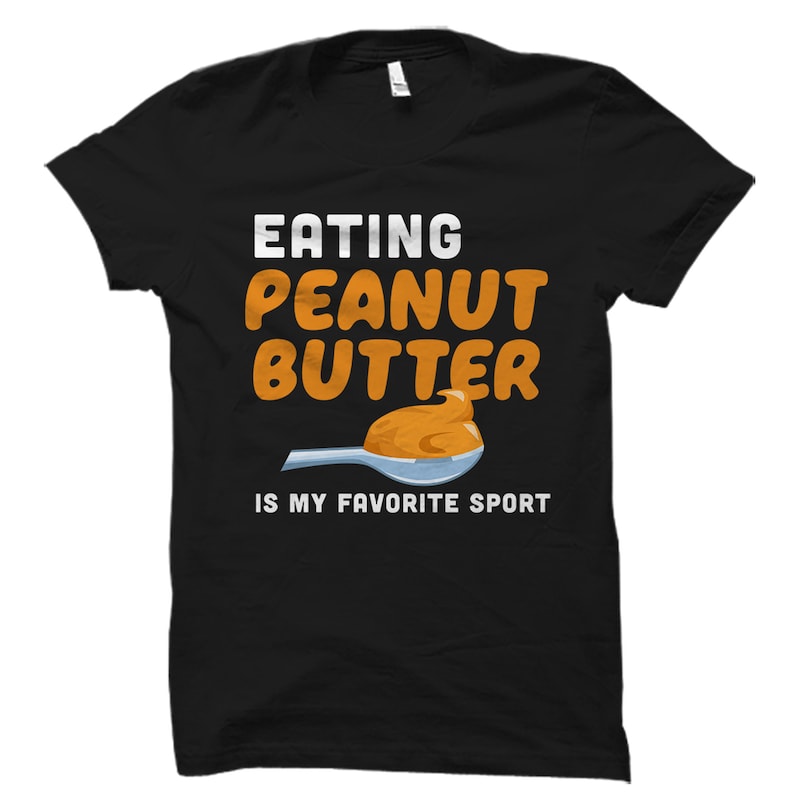 K&ouml;nnte beinhalten: Schwarzes T-Shirt mit wei&szlig;em Text, der lautet "Erdnussbutter essen ist mein Lieblingssport". &Uuml;ber dem Text befindet sich ein Cartoon-Bild eines L&ouml;ffels mit Erdnussbutter darauf.