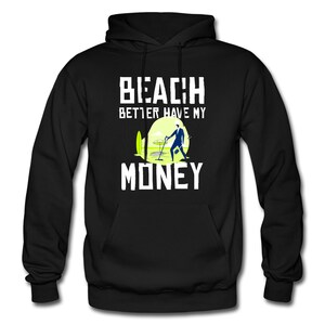 May include: Black hooded sweatshirt with white text that reads "Beach Better Have My Money". A cartoon illustration of a person with a metal detector is below the text.