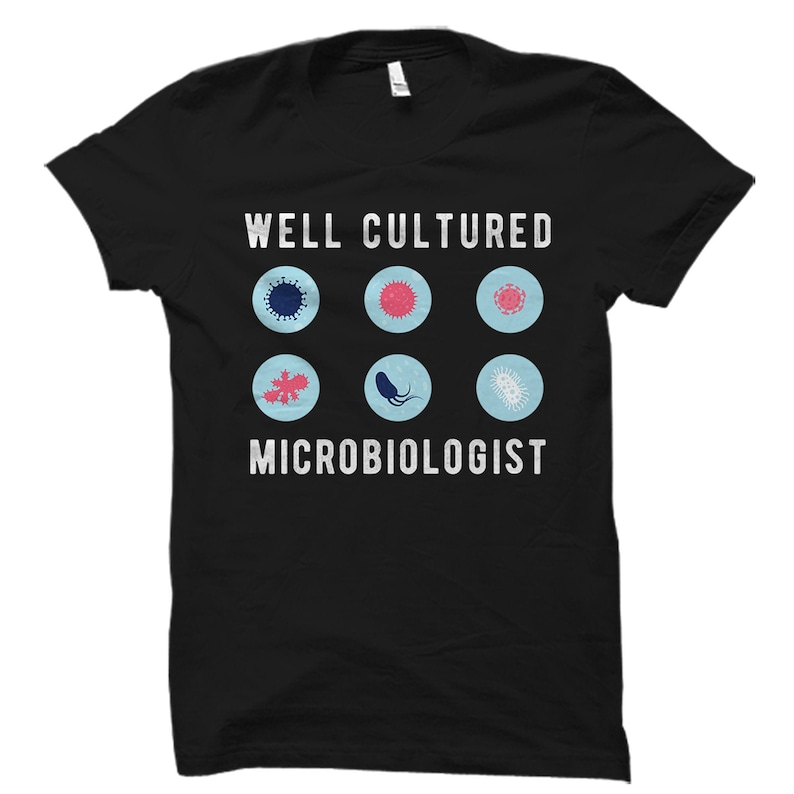 May include: Black t-shirt with the text "Well Cultured Microbiologist" and a row of six blue and white circles containing different bacteria and viruses.