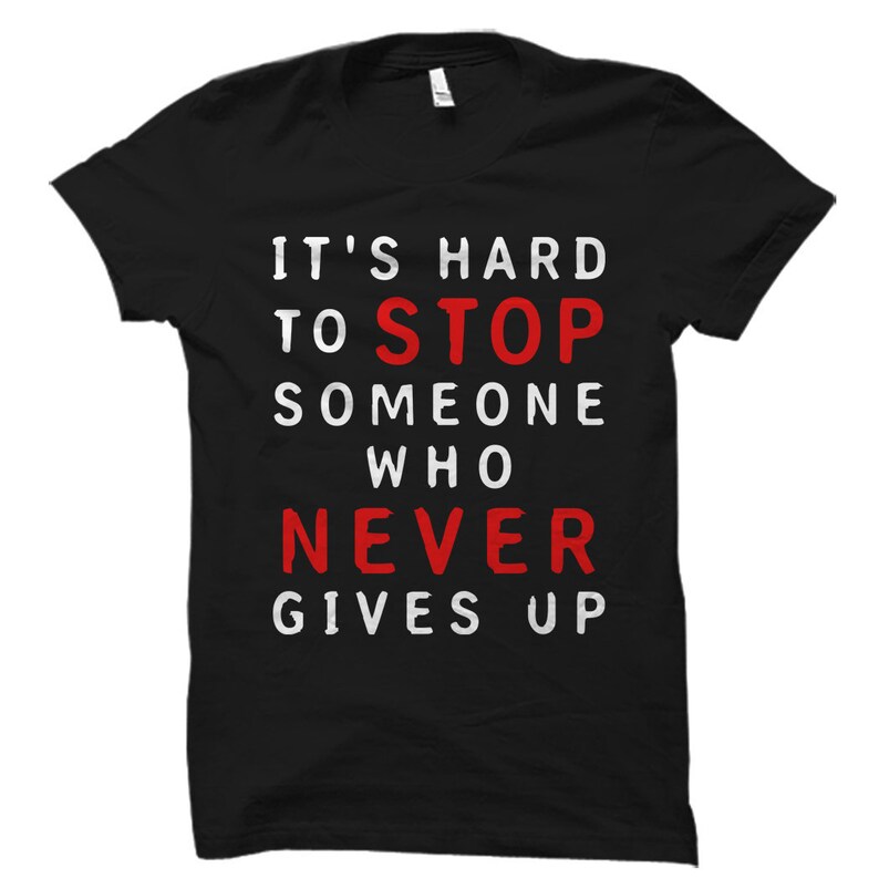 May include: Black t-shirt with white text that reads "It's hard to stop someone who never gives up". The word "never" is in red.