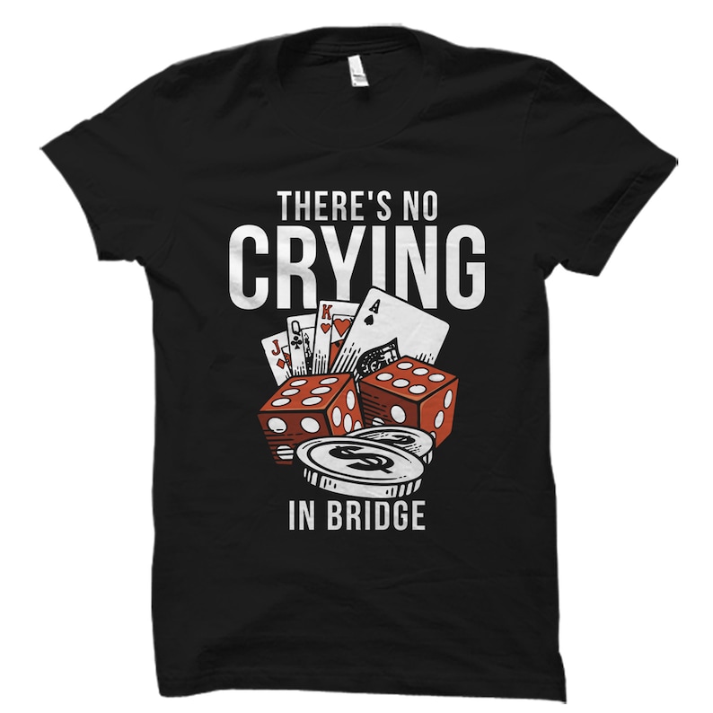 Pode incluir: Camiseta preta com um design gr&aacute;fico branco de cartas de jogo, dados e fichas de p&ocirc;quer. O texto "There's No Crying In Bridge" est&aacute; impresso na camiseta.