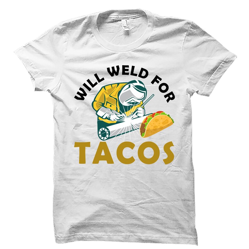 May include: White t-shirt featuring a cartoon welder in a yellow jacket and welding mask, welding a metal beam. A taco is next to the welder. The text reads "WILL WELD FOR TACOS" in black and gold.