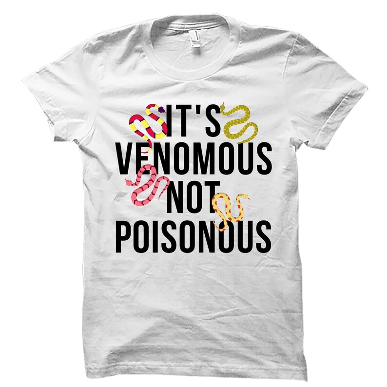 May include: White t-shirt with the text "IT'S VENOMOUS NOT POISONOUS" in black. The shirt features colorful snake illustrations in red, yellow, and pink. A crew neck, short-sleeved tee.