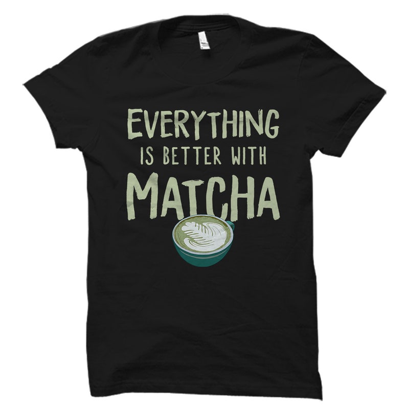 Puede incluir: Camiseta negra con el texto "Everything is better with Matcha" en verde y un latte matcha verde en una taza blanca con un platillo verde.