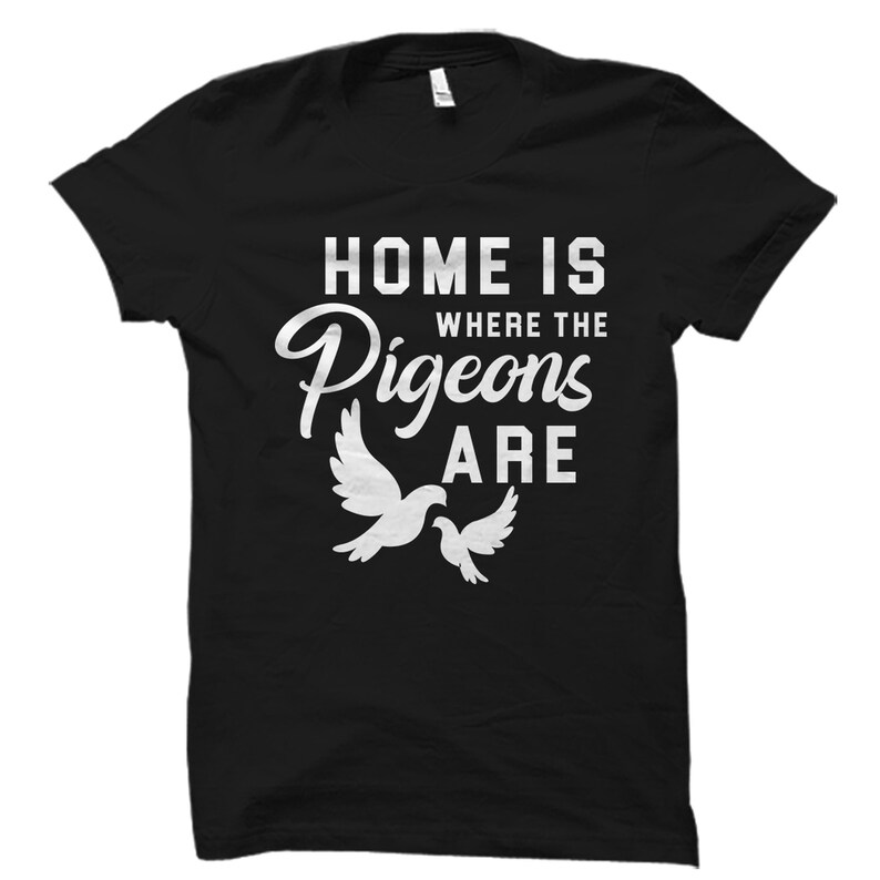 May include: Black t-shirt with white text that reads "Home is where the pigeons are". Two white pigeons are pictured below the text.