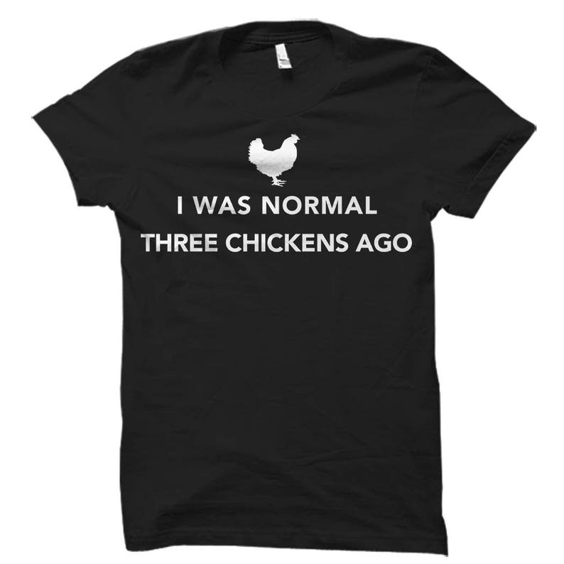 May include: Black t-shirt with white text that reads "I was normal three chickens ago". A white silhouette of a chicken is above the text.
