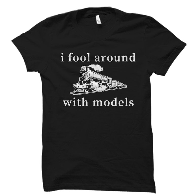 May include: Black t-shirt with white text that reads "i fool around with models" and a black and white illustration of a train.