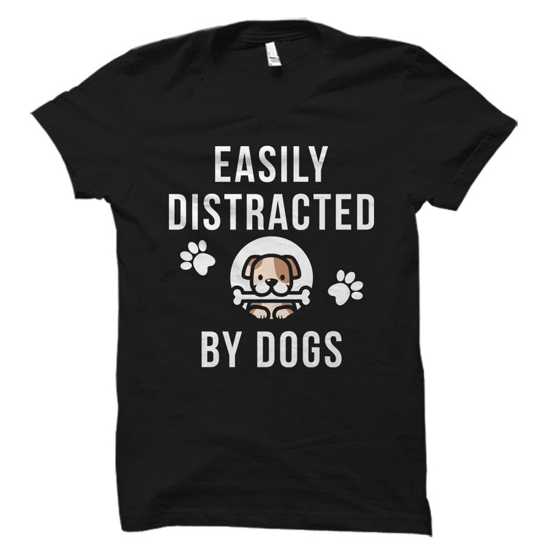 May include: Black t-shirt with white text that reads "Easily Distracted By Dogs". A cartoon dog with a bone is in the center of the text.