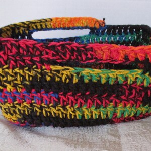 May include: A crocheted basket with a black base and colourful stripes of red, orange, yellow, green, and blue.