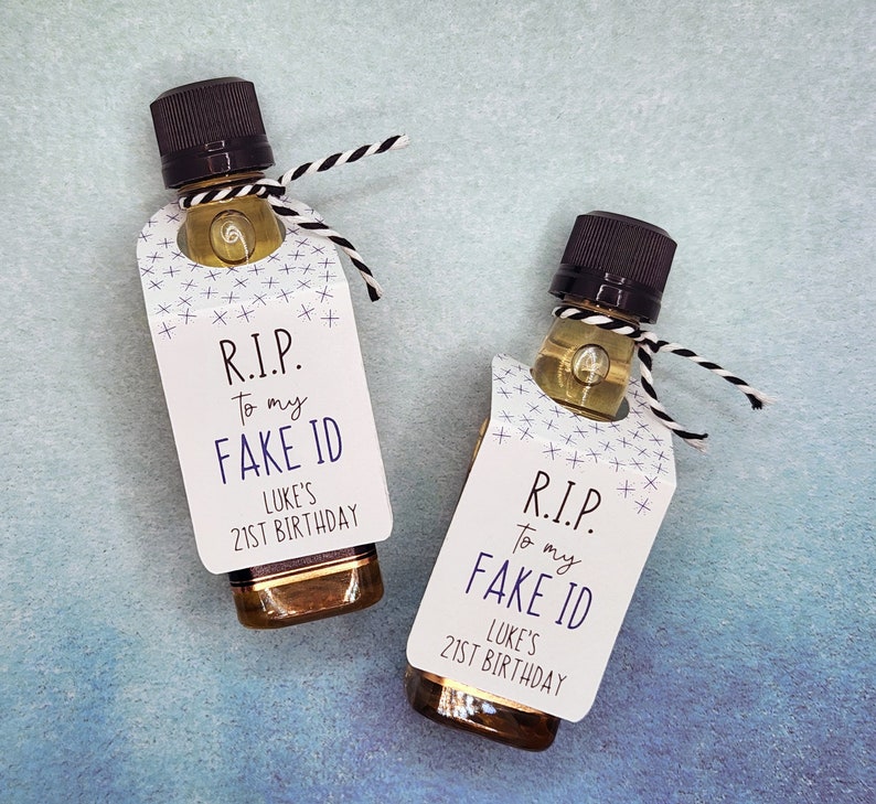 Pu&ograve; includere: Due piccole bottiglie di liquore con etichette bianche che recitano "R.I.P. To my FAKE ID LUKE'S 21ST BIRTHDAY" in nero e viola.