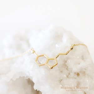 Serotonin molecule shaped pendant necklace are placed on white shiny rock. Not only its a symbol of well-being, but the shape is also simply cute n dainty !