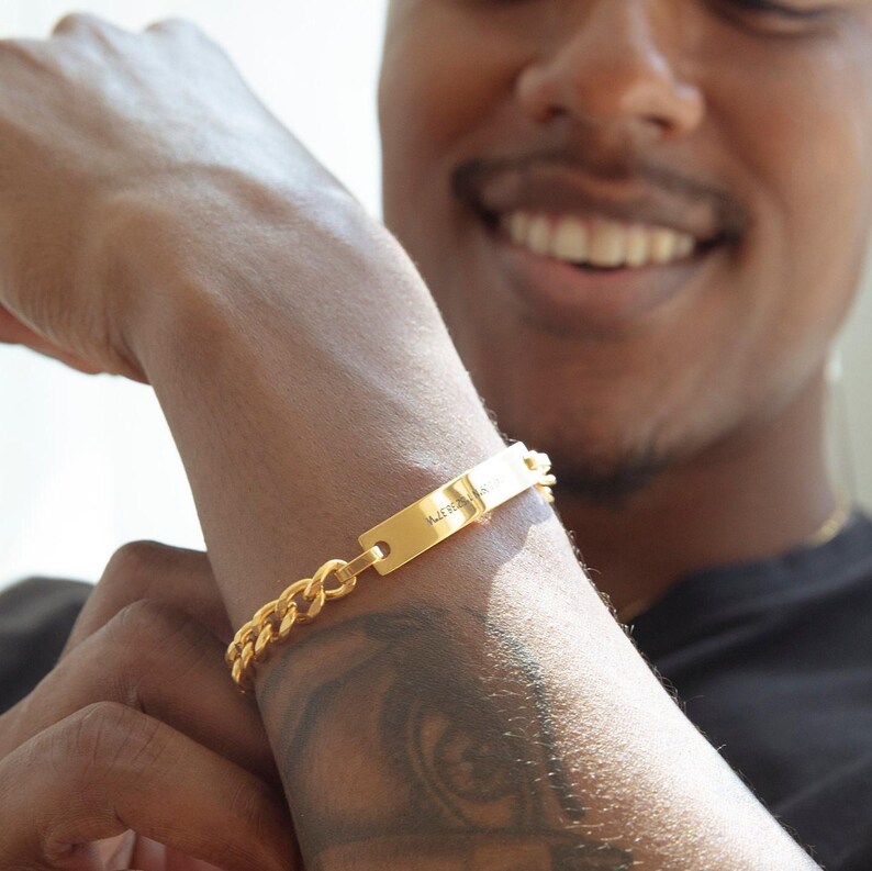 Pode incluir: Um bracelete de corrente dourada com uma etiqueta retangular que diz "Make It Happen".