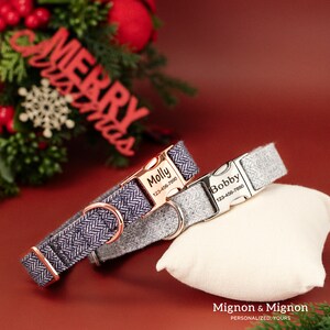 May include: Two personalized dog collars with engraved name tags and phone numbers. The collars are grey and navy blue with a herringbone pattern. The name tags are silver and rose gold.
