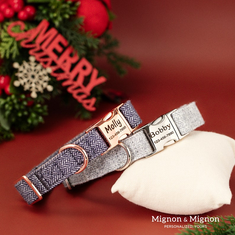 May include: Two personalized dog collars with engraved name tags and phone numbers. The collars are grey and navy blue with a herringbone pattern. The name tags are silver and rose gold.