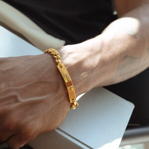 Pode incluir: Um bracelete de corrente dourada com uma etiqueta retangular que diz "Gratid&atilde;o &eacute; a melhor atitude".