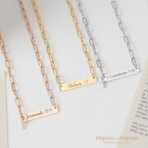 May include: Three gold, silver, and rose gold necklaces with a small cross charm and a rectangular bar pendant with engraved text. The text on the pendants reads "Nahum 1:7", "2 Corinthians 7:10", and "Jeremiah 29:11".