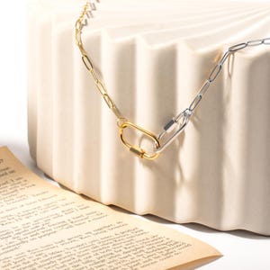 May include: Two gold and silver chain necklaces with a clasp closure. The chains are linked together at the clasps.
