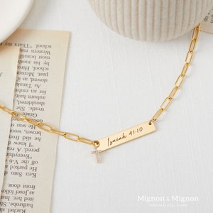 May include: A gold chain necklace with a small cross charm and a rectangular pendant inscribed with "Isaiah 41:10".