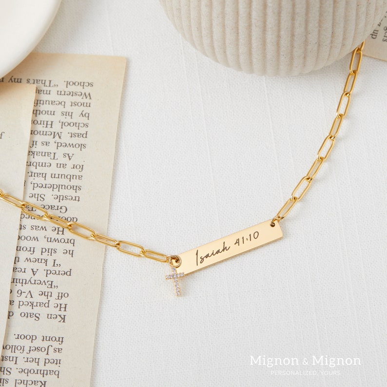 May include: A gold chain necklace with a small cross charm and a rectangular pendant inscribed with "Isaiah 41:10".