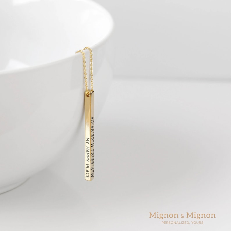 May include: Gold bar necklace with the coordinates 40&deg;45&prime;32&Prime;N 73&deg;59' 6" W and the text "MY HAPPY PLACE" engraved on it.