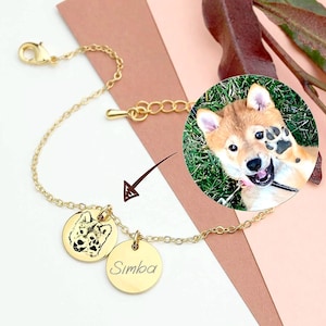 Könnte beinhalten: Goldkette Armband mit zwei Anhängern. Ein Anhänger zeigt ein Schwarzweißfoto eines Hundefaces. Der andere Anhänger ist mit dem Namen "Simba" graviert.