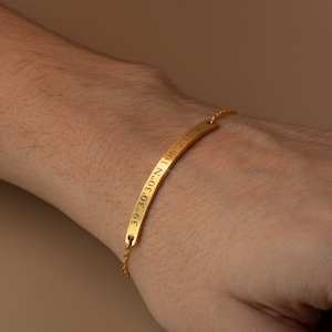 May include: A gold bracelet with a thin chain and a flat bar engraved with the coordinates "39°30'30"N 106°21'51"W".