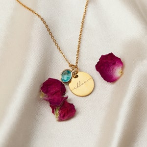 May include: Gold necklace with a round pendant that says "chloe" in cursive script. The pendant is attached to a small blue gemstone.
