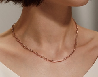 May include: A rose gold chain necklace with a small rectangular pendant. The pendant has a subtle inscription.