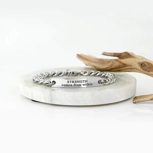 Pode incluir: Pulseira de prata com corrente tran&ccedil;ada e uma etiqueta retangular que diz "STRENGTH comes from within".