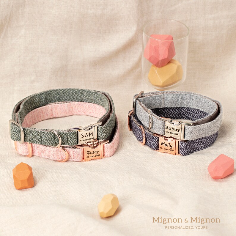 May include: Three personalized dog collars with engraved name tags. The collars are made of a herringbone patterned fabric in green, gray, and blue. The name tags are silver with rose gold accents. The text on the tags reads "Sam", "Bailey", "Bobby", and "Molly".