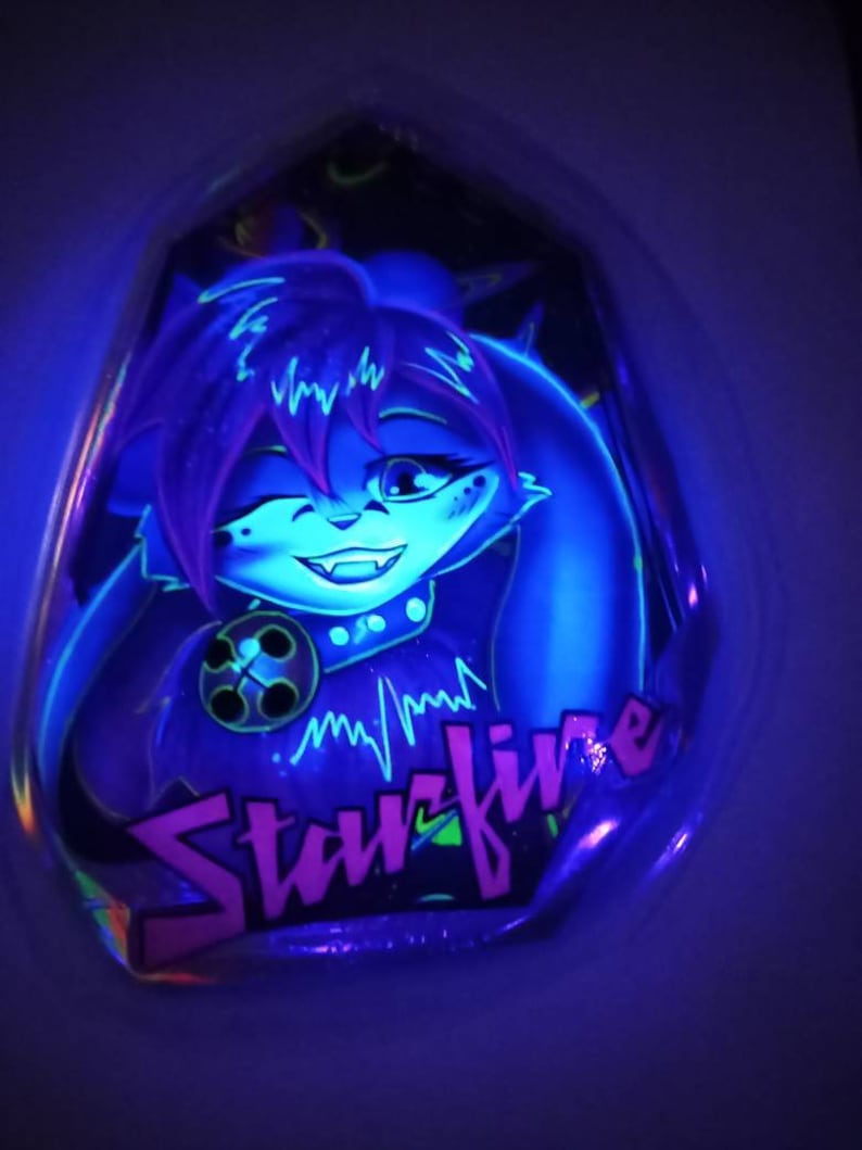 May include: A neon-lit, stylized illustration of a blue cartoon character with purple hair and a collar. The character is winking and smiling. The name "Starfire" is written in pink and green neon lettering.