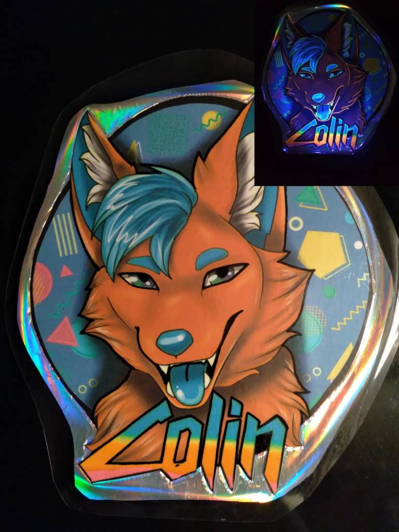 May include: A holographic sticker featuring a cartoon fox with orange fur, blue hair, and a blue tongue. The sticker has the name "Zolin" in colorful text. The background is light blue with geometric shapes.