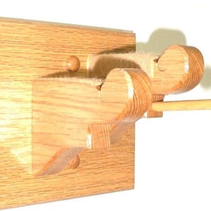 May include: A wooden wall-mounted coat rack with two hooks and a dowel rod. The rack is made of light brown wood and has a simple design.