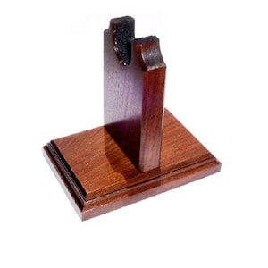 May include: A wooden display stand with a rich, dark brown finish. The stand features a rectangular base with a raised edge and a vertical support with a curved top, designed to hold an item. The stand is likely for displaying a decorative object.