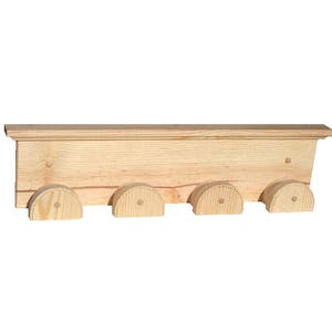 May include: A natural wood shelf with four semi-circular hooks. The shelf is made of light-colored wood and has a simple, rustic design. The hooks are evenly spaced along the bottom edge. This shelf is perfect for a child's room or a farmhouse-style home.