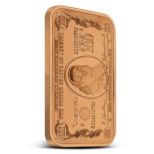 May include: A gold-colored bar with a design resembling a $100 bill. The bar features a portrait of Benjamin Franklin and the text "UNITED STATES OF AMERICA" and "ONE HUNDRED DOLLARS".