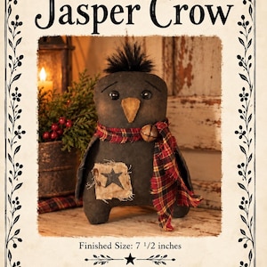 Op de afbeelding: Een zwarte stoffen kraaienpop met een beige snavel, zwarte knoopogen en een plukje zwart haar. Het draagt een rood-gele sjaal met een metalen belletje en een beige lapje met een zwarte ster. Tekst: Jasper Crow en Finished Size: 19,05 cm.