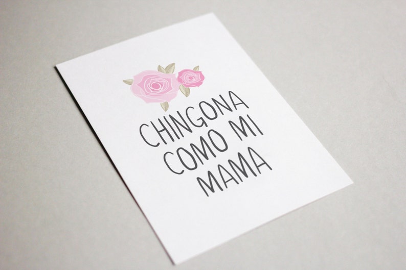 Op de afbeelding: Een witte kaart met twee roze rozen en de tekst "CHINGONA COMO MI MAMA" in zwart.