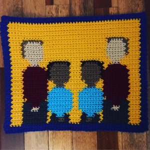 May include: Crocheted wall hanging featuring four figures standing in a row. The figures are crocheted in different colors, including brown, blue, and purple. The background is yellow.