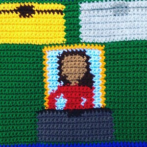 May include: A crocheted square with a green background, a yellow square with a brown eye, a white square, a gray square, and a red, brown, and white figure in a blue and yellow frame.