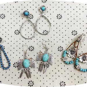 May include: An assortment of silver-toned earrings with turquoise accents. Styles include teardrop, beaded, and bird-shaped designs. The earrings are displayed on a white surface with a black floral pattern.