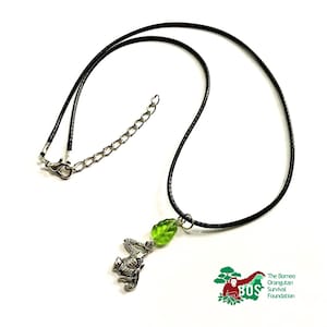 May include: A black cord necklace with a silver orangutan charm and a green glass leaf pendant. The Borneo Orangutan Survival Foundation logo is visible in the bottom right corner.