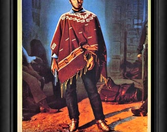 May include: A framed movie poster for Per Qualche Dollaro in Piu featuring Clint Eastwood wearing a brown hat and a patterned maroon poncho with fringe. He holds a revolver while standing in a dimly lit room with a saddle on the floor.