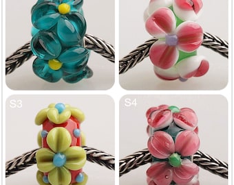 Peut inclure: Quatre perles de verre avec des motifs floraux. Les perles sont turquoise, rose, rouge et verte avec des accents jaunes, blancs et bleus. Les perles sont sur une chaîne argentée.