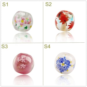 May include: Four glass beads with different floral designs. The beads are white, red, pink, and blue with gold accents. The beads are round and have a glossy finish.