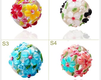 May include: Four glass beads with floral designs. The beads are white with different colored flowers. The beads are labeled S1, S2, S3, and S4.