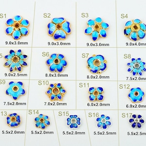以下が含まれることがあります： 青いエナメルペタルが付いた、金色の金属製の花型のビーズのコレクション。各ビーズは異なるデザインとサイズで、直径5.5mmから9.0mmまであります。ビーズにはS1からS17までのラベルが付いています。