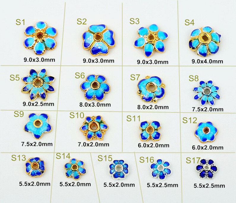 以下が含まれることがあります： 青いエナメルペタルが付いた、金色の金属製の花型のビーズのコレクション。各ビーズは異なるデザインとサイズで、直径5.5mmから9.0mmまであります。ビーズにはS1からS17までのラベルが付いています。